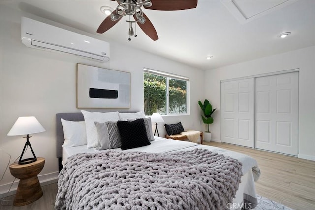 bedroom with ceiling fan, hardwood / wood-style floors, a closet, and an AC wall unit