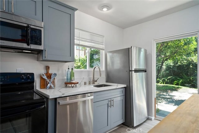 kitchen with light stone counters, sink, and appliances with stainless steel finishes