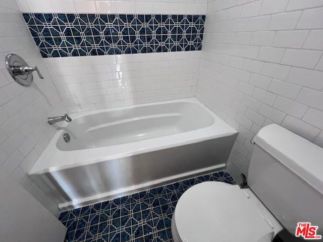 bathroom featuring tile walls, tiled shower / bath combo, and toilet