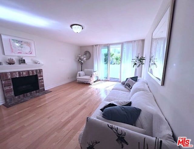 living room with a brick fireplace and light wood-type flooring