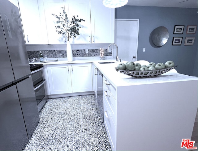 kitchen with sink, white cabinetry, backsplash, stainless steel appliances, and kitchen peninsula