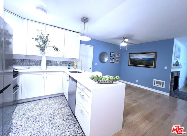 kitchen with sink, decorative light fixtures, stainless steel dishwasher, kitchen peninsula, and white cabinets