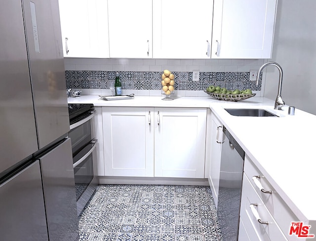 kitchen featuring tasteful backsplash, white cabinetry, appliances with stainless steel finishes, and sink