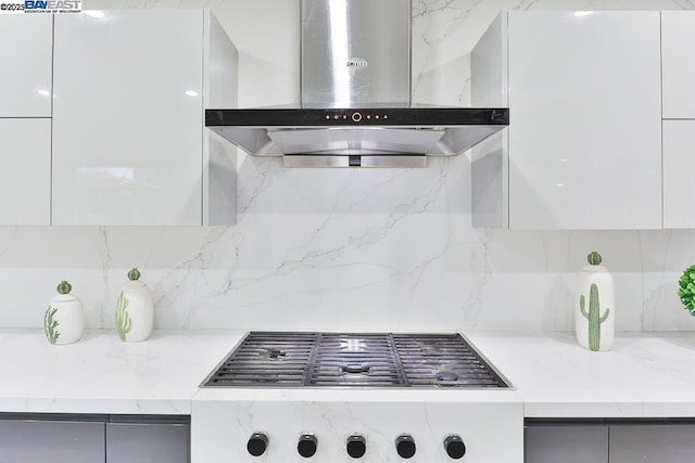 kitchen with range hood, cooktop, and white cabinets