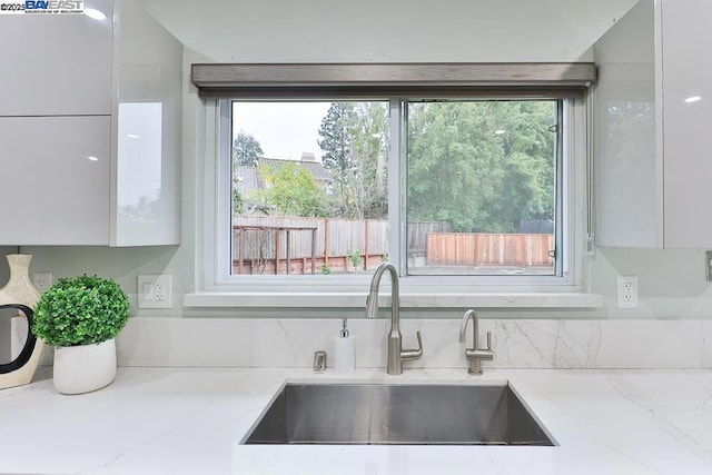 details featuring light stone countertops, sink, and white cabinets