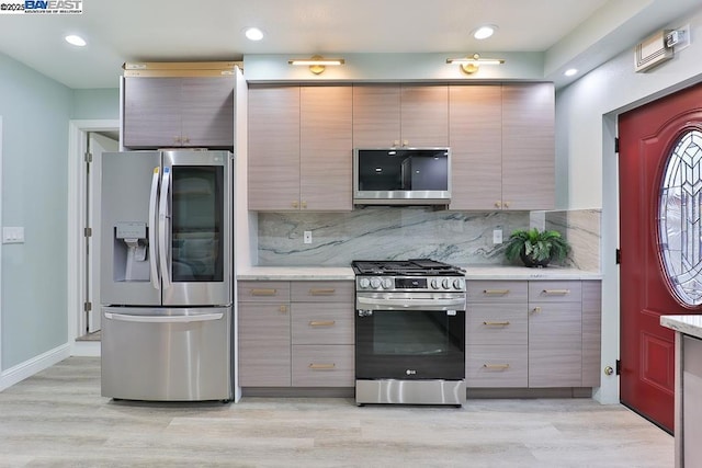 kitchen featuring gray cabinetry, backsplash, light wood-type flooring, and appliances with stainless steel finishes