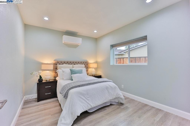 bedroom featuring light wood-type flooring and an AC wall unit