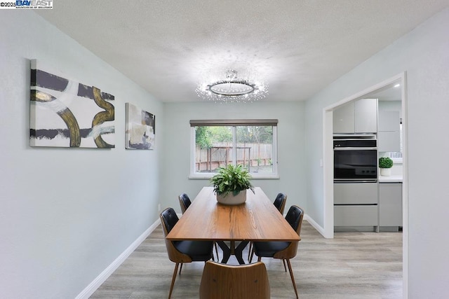 dining space featuring light hardwood / wood-style flooring and a textured ceiling