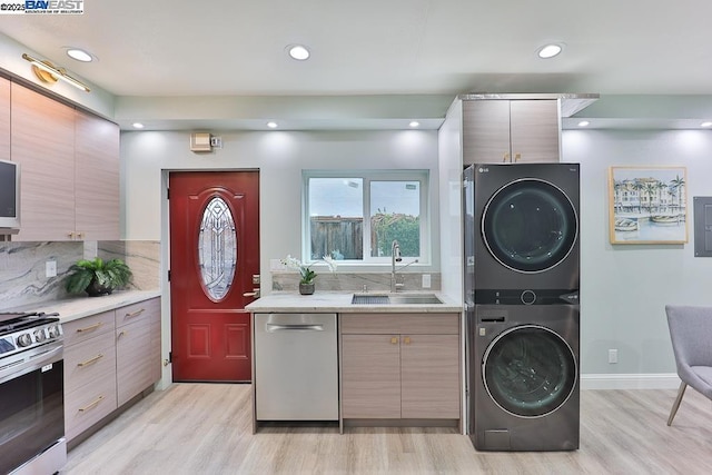 washroom featuring stacked washer and dryer, sink, and light hardwood / wood-style floors