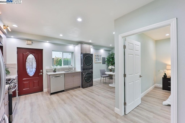 kitchen with sink, light hardwood / wood-style flooring, stacked washer and clothes dryer, and appliances with stainless steel finishes