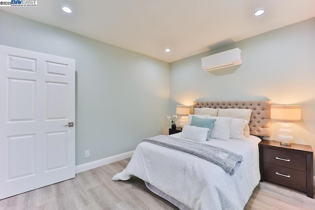 bedroom with light hardwood / wood-style floors and an AC wall unit