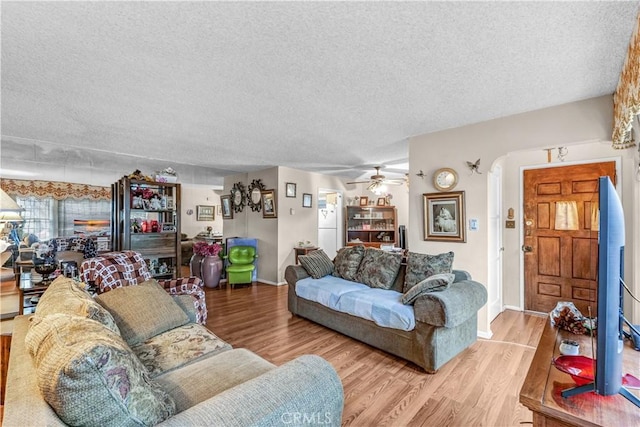 living room featuring ceiling fan, a textured ceiling, and light hardwood / wood-style floors