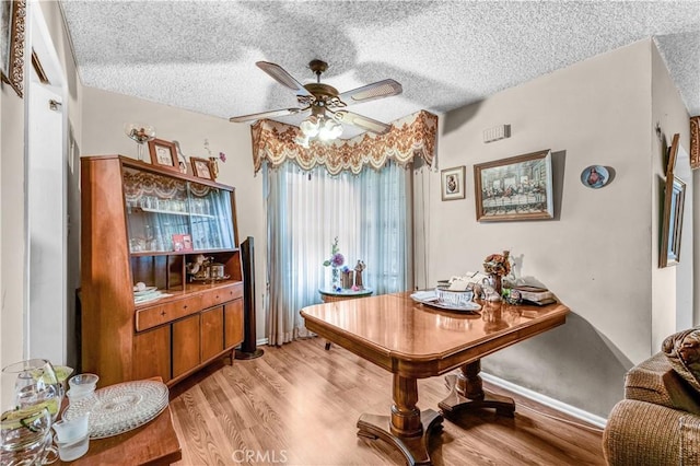 dining space with ceiling fan, a textured ceiling, and light hardwood / wood-style flooring