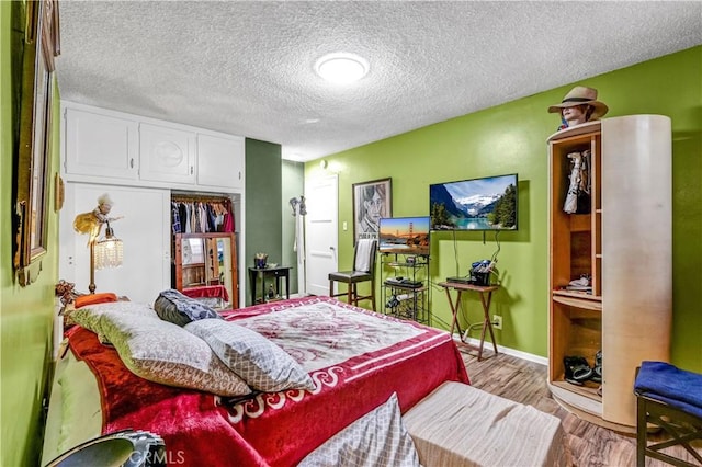 bedroom with a textured ceiling, light wood-type flooring, and a closet