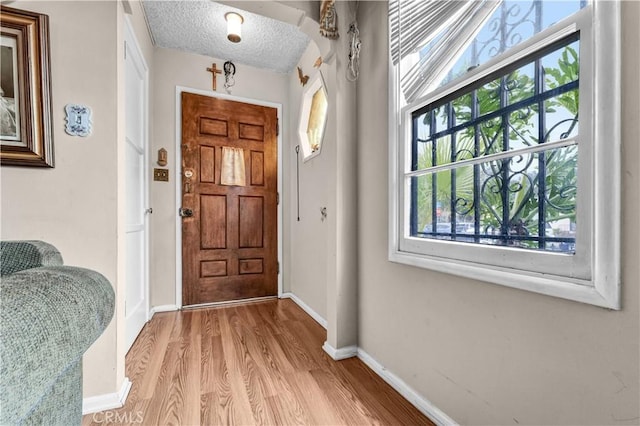 foyer entrance featuring light hardwood / wood-style floors and a textured ceiling