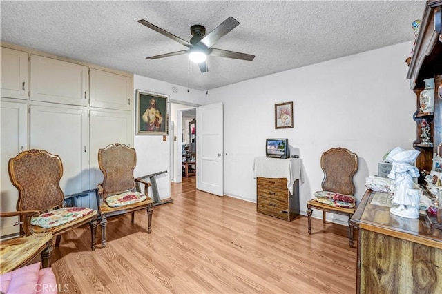 sitting room with a textured ceiling, light hardwood / wood-style flooring, and ceiling fan