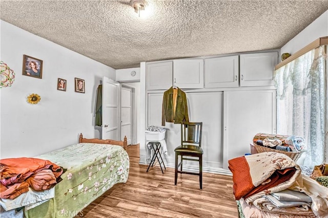 bedroom with a closet, a textured ceiling, and light hardwood / wood-style flooring