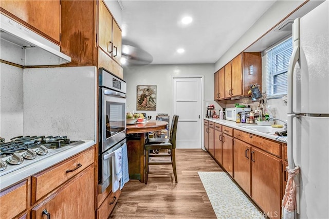 kitchen with sink, white appliances, and light hardwood / wood-style flooring