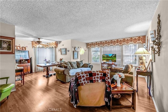 living room with ceiling fan, hardwood / wood-style floors, and a textured ceiling