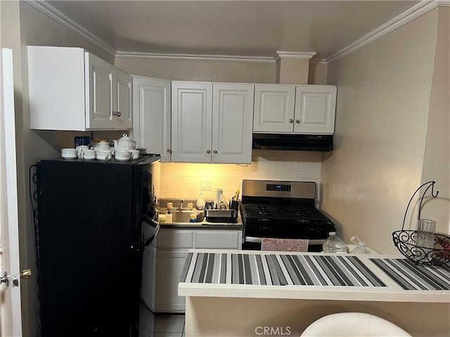 kitchen with stainless steel gas range oven, white cabinetry, black fridge, ornamental molding, and decorative backsplash