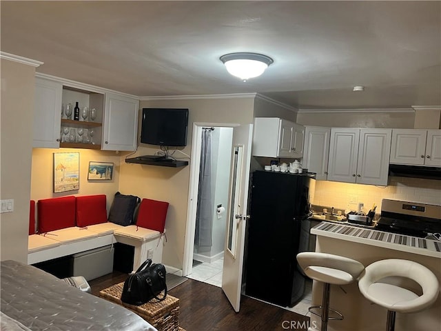 kitchen featuring black fridge, white cabinets, crown molding, and backsplash