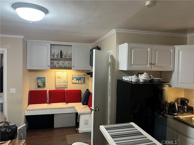 kitchen featuring tasteful backsplash, white cabinetry, ornamental molding, and dark hardwood / wood-style floors