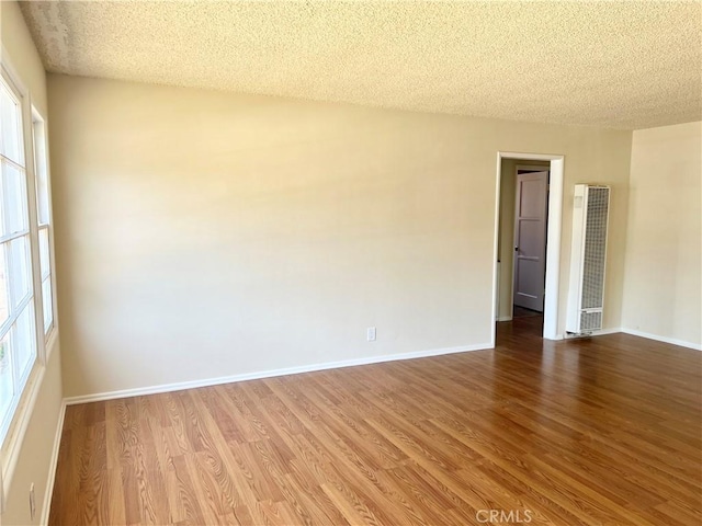 2441 W Repetto Ave, Montebello, CA 90640 - empty room with a heating unit, wood finished floors, a textured ceiling, plenty of natural light, and baseboards