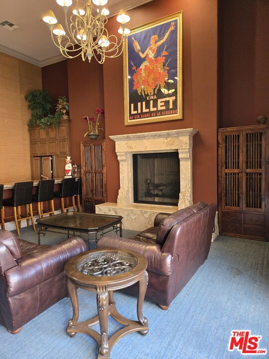 living room with crown molding, a premium fireplace, and a chandelier