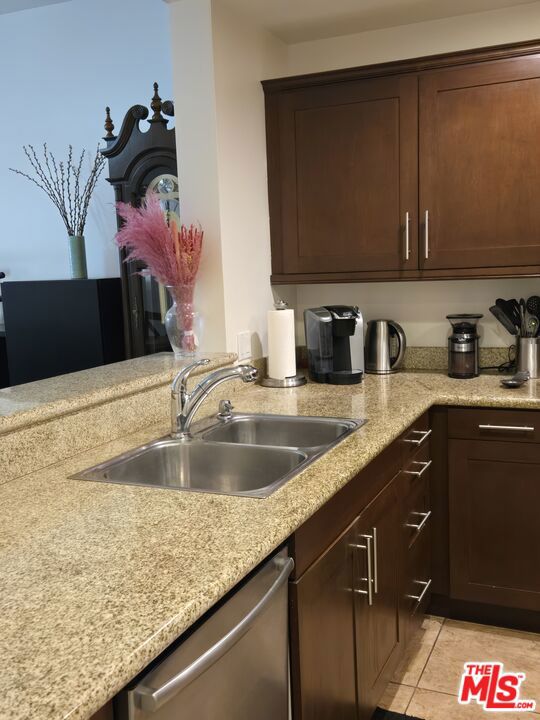 kitchen featuring light tile patterned flooring, sink, stainless steel dishwasher, and dark brown cabinetry