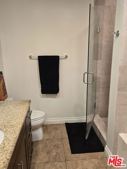 bathroom with vanity, a shower with shower door, tile patterned floors, and toilet