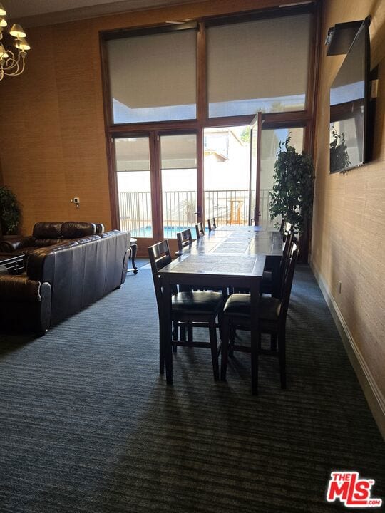 dining space with dark carpet and a notable chandelier