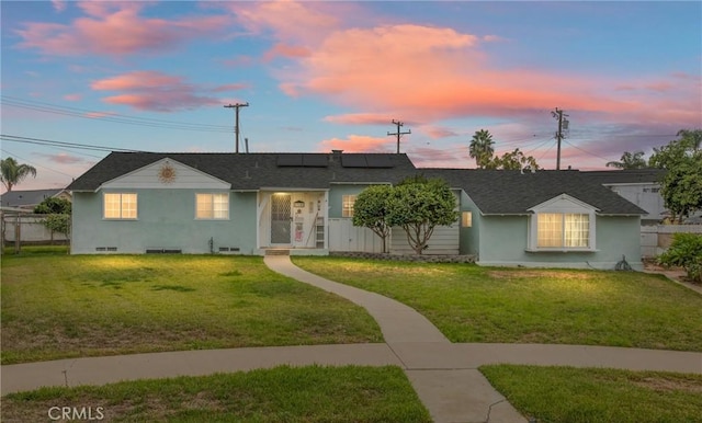 single story home with a lawn and solar panels