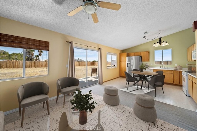 living room with vaulted ceiling, sink, ceiling fan with notable chandelier, and a textured ceiling