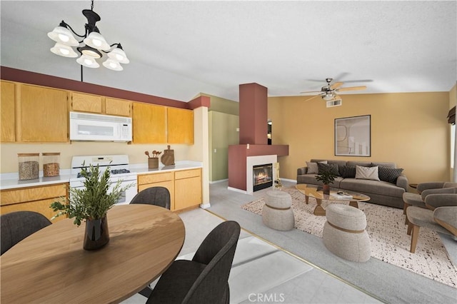 interior space featuring ceiling fan with notable chandelier, pendant lighting, and white appliances