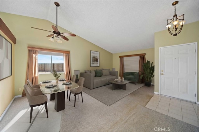 carpeted living room with ceiling fan with notable chandelier and vaulted ceiling