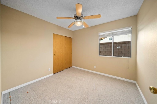 carpeted empty room featuring ceiling fan and a textured ceiling