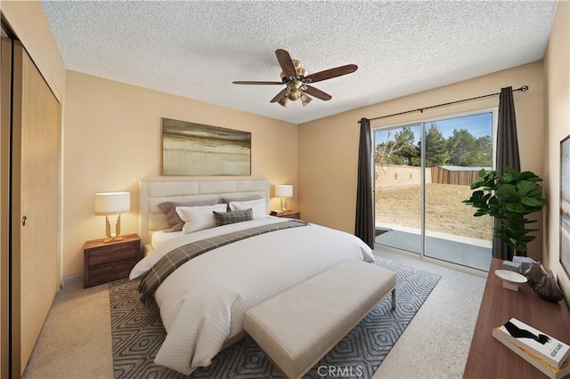 carpeted bedroom with a textured ceiling, access to exterior, and ceiling fan