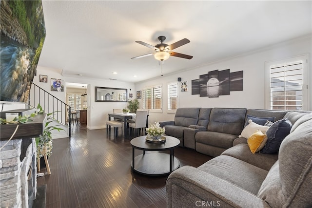 living area with crown molding, dark wood finished floors, stairway, a ceiling fan, and baseboards