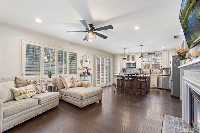 living area with ornamental molding, visible vents, dark wood finished floors, and a fireplace