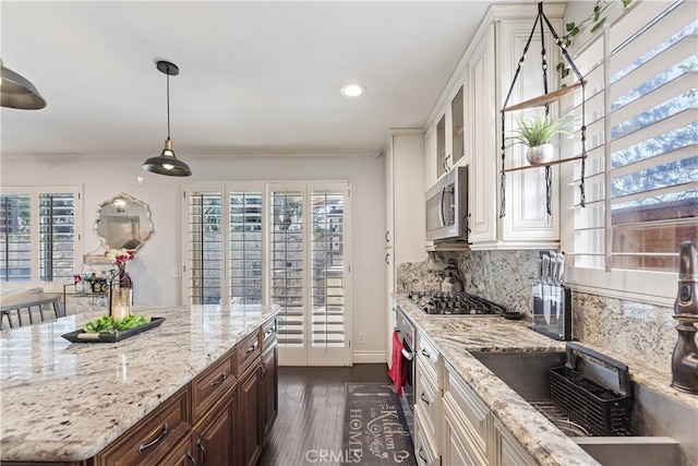 kitchen featuring white cabinets, dark wood finished floors, decorative backsplash, light stone countertops, and stainless steel appliances