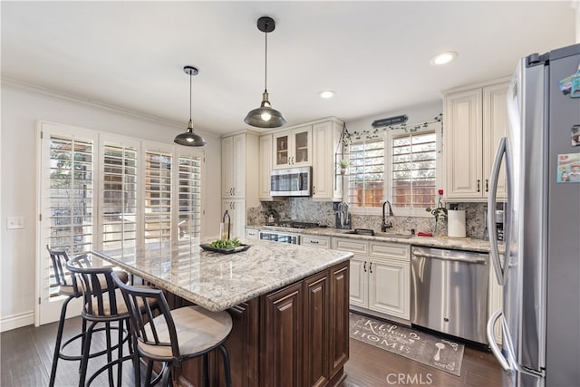 kitchen with stainless steel appliances, a sink, a center island, and decorative backsplash