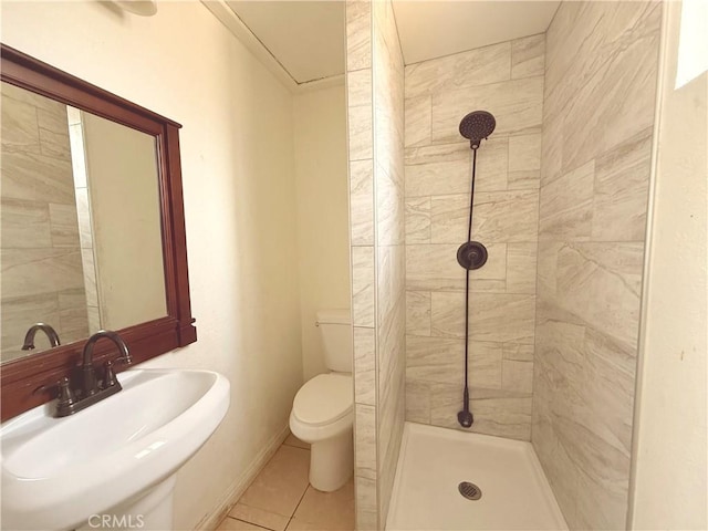 bathroom with a tile shower, sink, tile patterned floors, and toilet