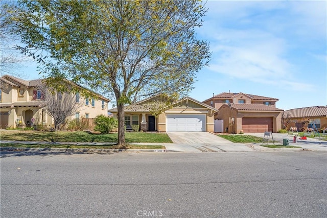 view of front of home featuring driveway, a tile roof, a garage, and stucco siding