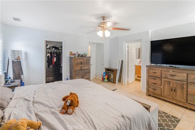 bedroom featuring a walk in closet, light tile patterned floors, a closet, visible vents, and connected bathroom