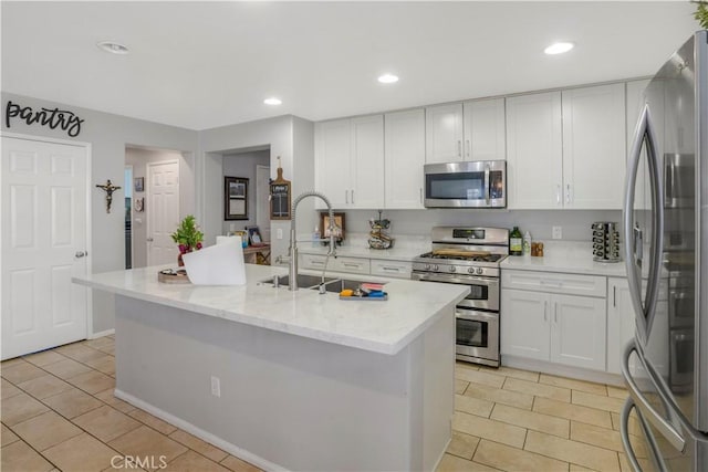 kitchen featuring appliances with stainless steel finishes, white cabinets, a sink, and light stone countertops