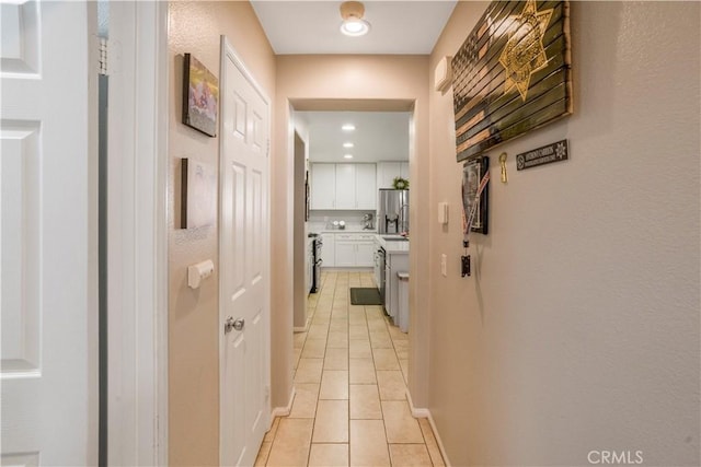 hallway featuring recessed lighting, baseboards, and light tile patterned floors