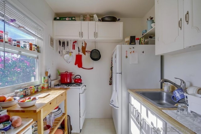 kitchen with white cabinetry, sink, and white appliances