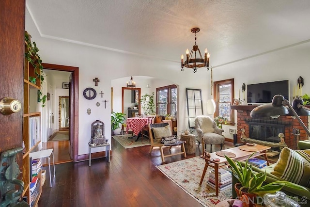 living room with a notable chandelier, a fireplace, dark hardwood / wood-style floors, and a textured ceiling