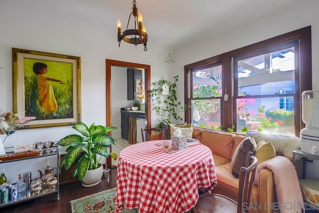 dining space with dark wood-type flooring and an inviting chandelier