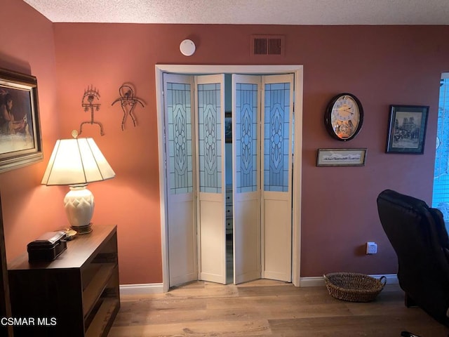 foyer entrance with light hardwood / wood-style flooring and a textured ceiling